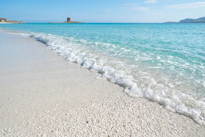 Détail épuré de l'eau turquoise et du sable fin à La Pelosa